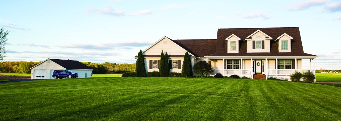 A house with a garage and a large front yard with a manicured lawn